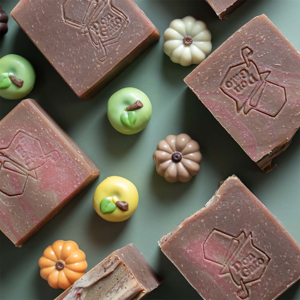 Pumpkin Apple Artisan Soap bars over green background and some candys around.