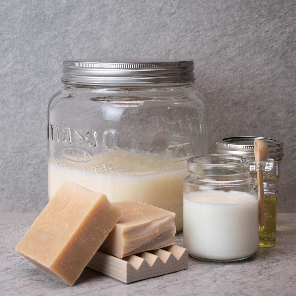 Handcrafted Goat Milk soap by Jabonera Don Gato from the Bestsellers collection, shown with glass jars of milk and oils on gray background.
