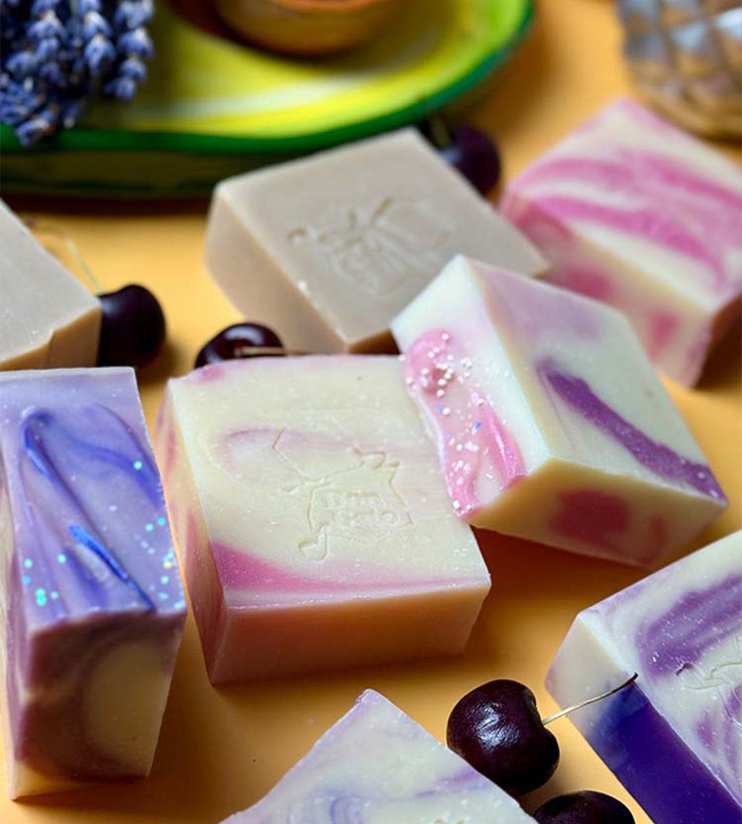 Juicy Spell artisan soap by Don Gato, with purple and pink swirls on a yellow background with cherries.