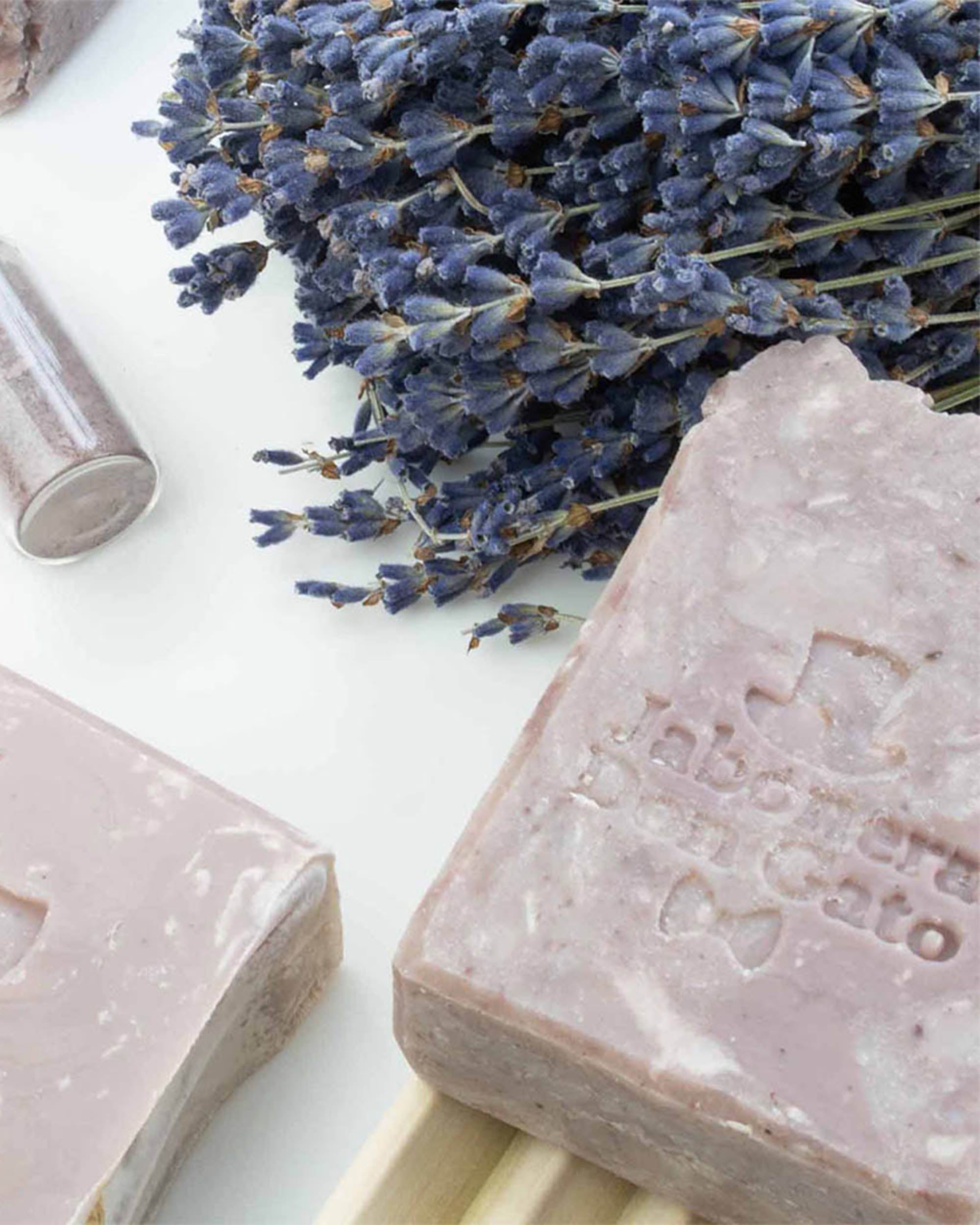 Natural soaps by Don Gato Soap Co. presented in soft tones with botanical elements, photographed in bright natural light.

