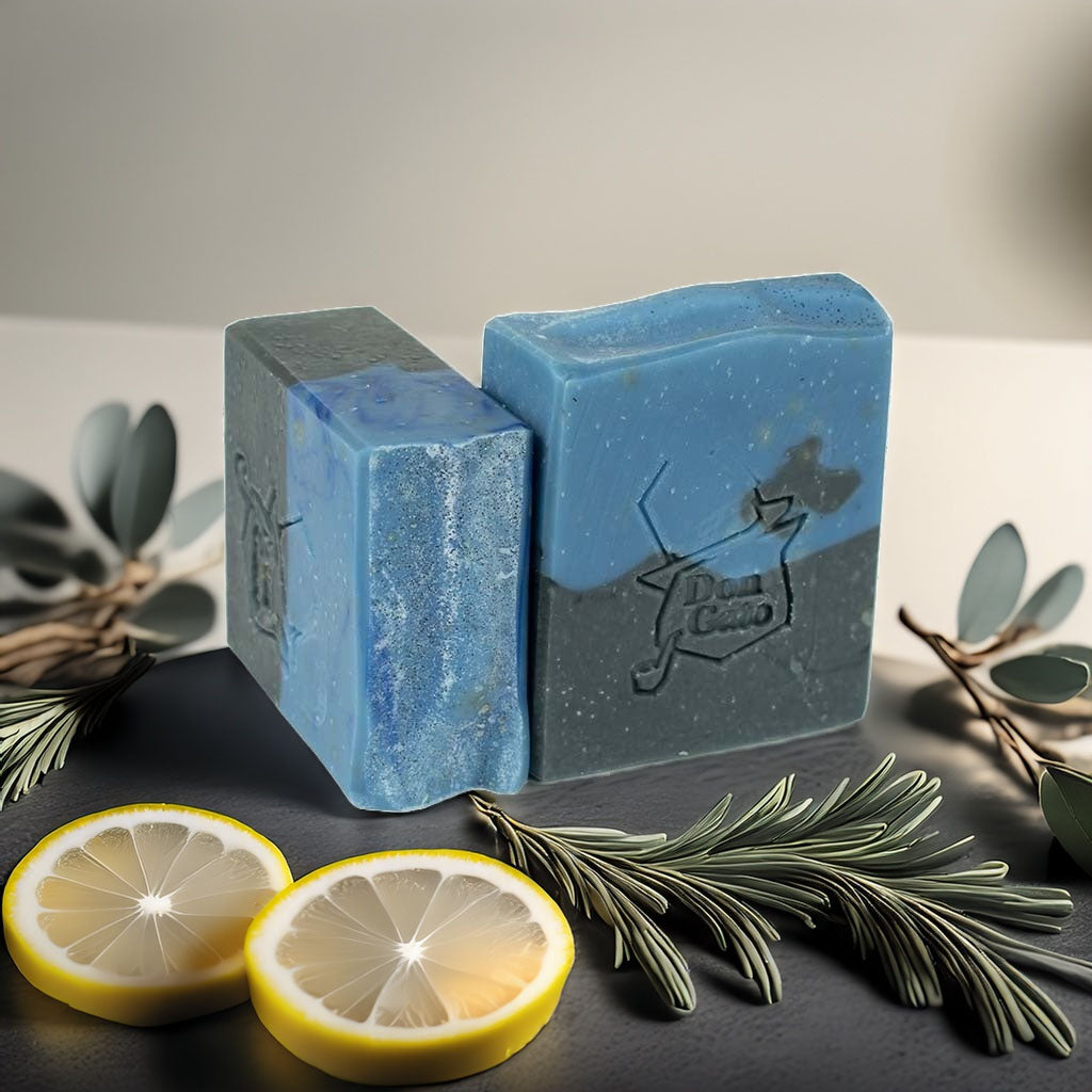 Blue and charcoal duo-tone artisan soap with lemon slices and rosemary, captured in bright natural light.