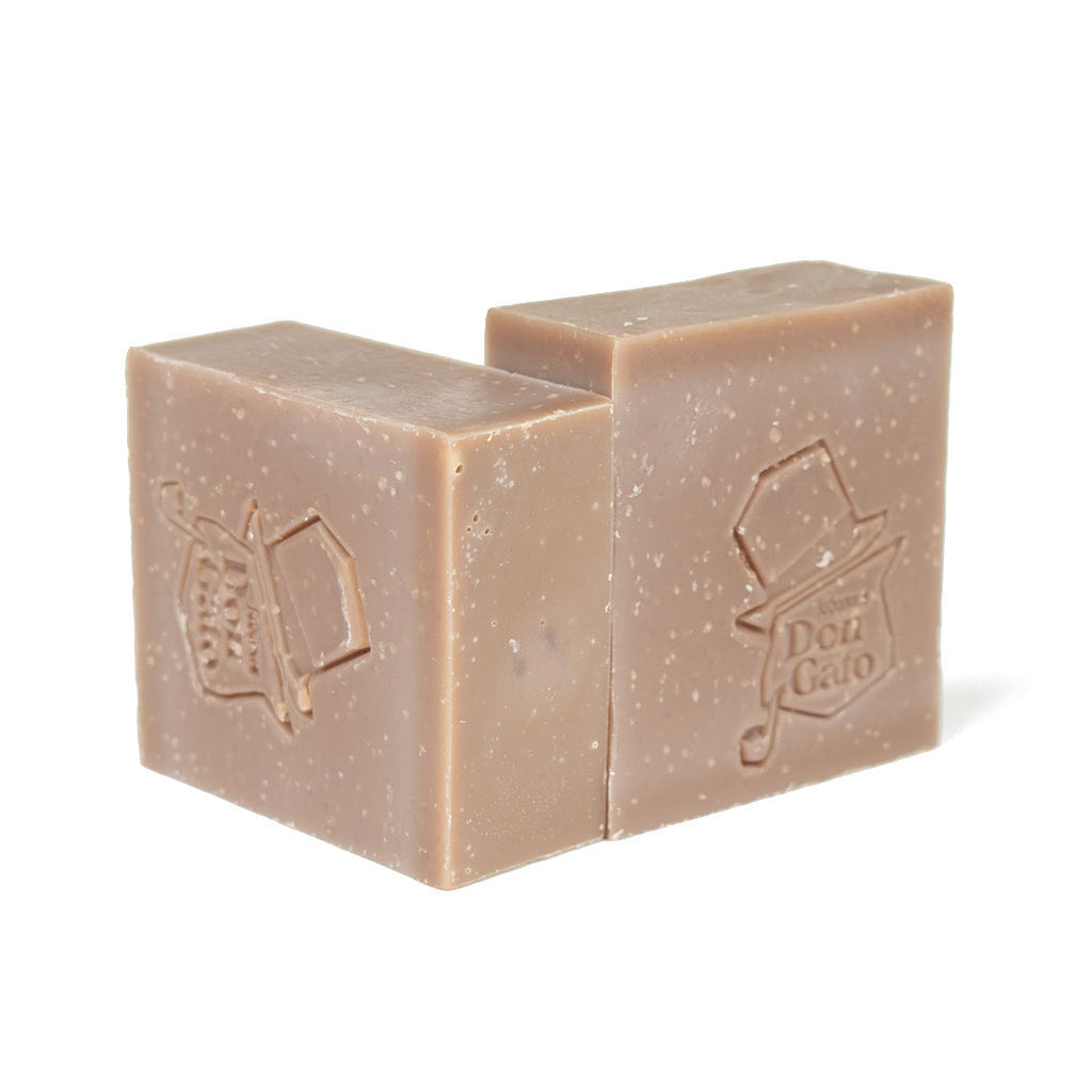 Two lilac-gray Don Gato Cashmere soap bars with embossed logos in bright natural light